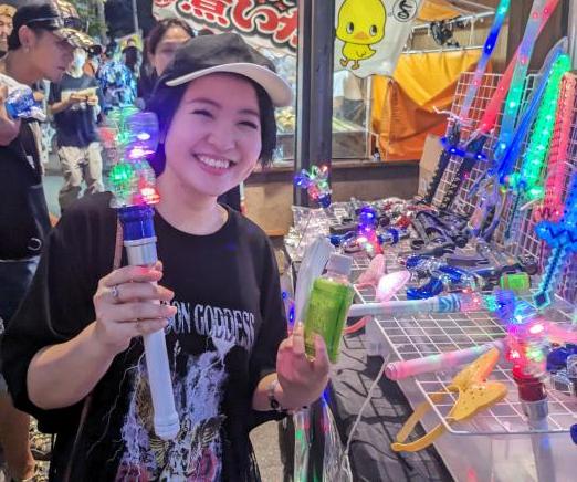 キラキラ光る玩具を手に笑顔を見せる若い女性の写真