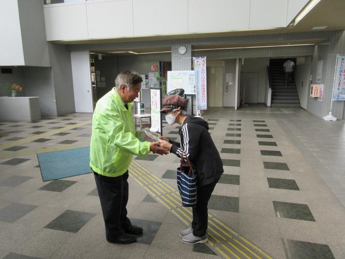 人権擁護委員が市役所に来た女性に啓発品を渡している写真