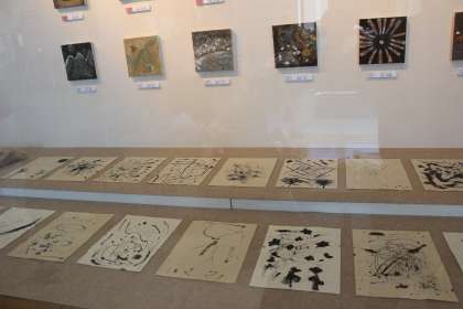 展示スペースの床上および壁面に色紙様の作品が並べられて展示されている