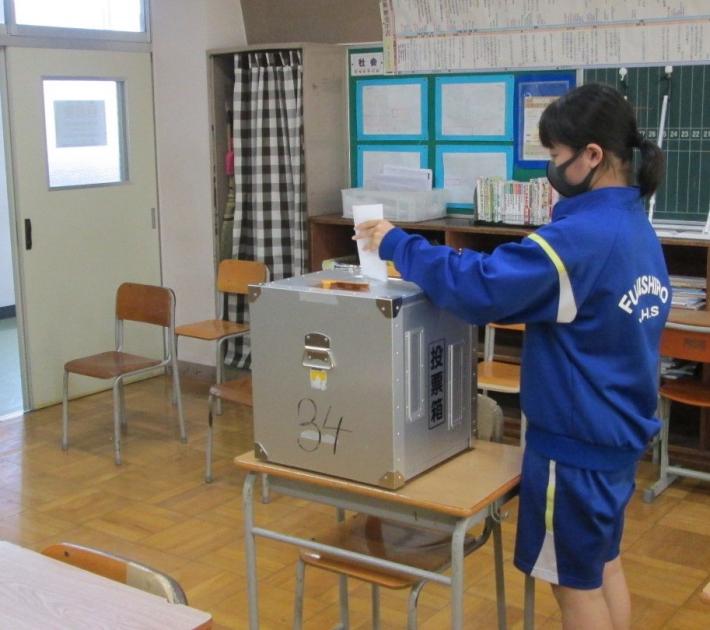 藤代中学校の生徒会選挙にて、候補者名を記載した投票用紙を投票箱に入れる様子