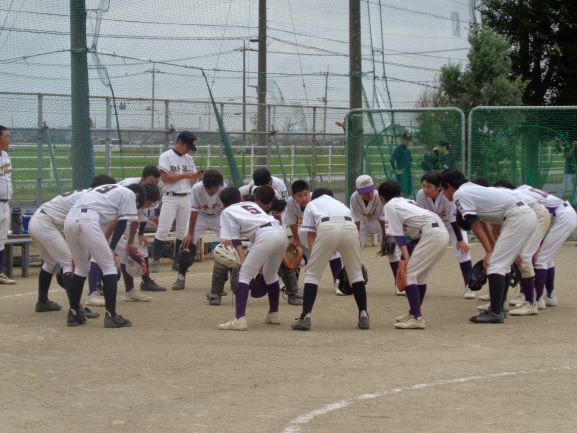 藤代軟式野球部員が円陣を組んでいます。グラウンドで膝に手をつけ、地面を見るような姿で円陣を組む生徒たちの写真。