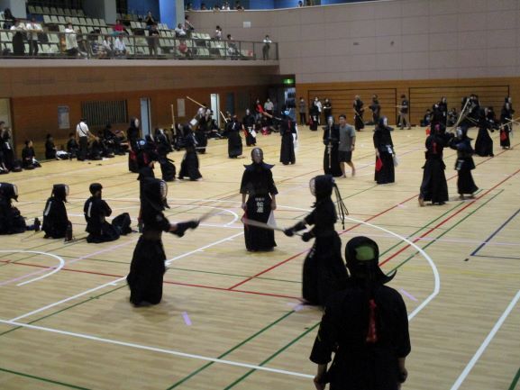 剣道団体戦の様子。体育館の中で、剣道着を着た人たちが試合をしている様子を上のほうから撮影した写真。