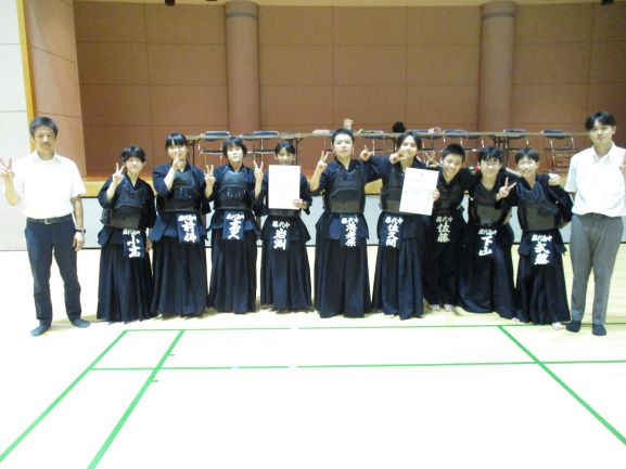 藤代剣道クラブの生徒たち。体育館の中で先生を両脇に、剣道着を着た生徒たちが並んで記念撮影している様子。