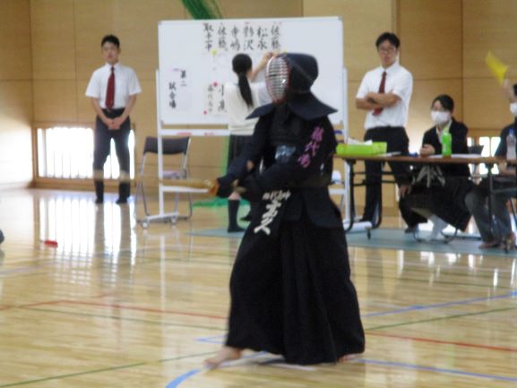 剣道新人戦で戦う生徒。体育館内で、剣道着、面をつけた人が試合中の様子。