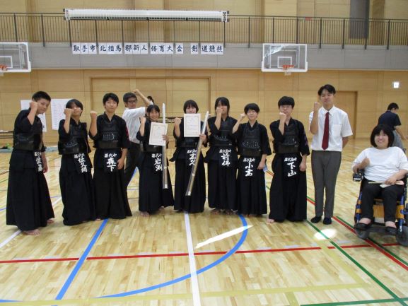 剣道部員たちと顧問の先生全体。先生の横に一列にならび、ガッツポーズをしている生徒たち。