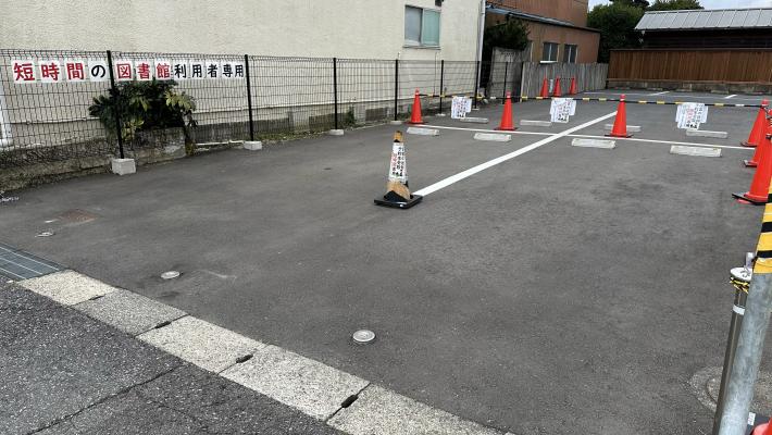 （正面）短時間利用者専用駐車場。「短時間の図書館利用者専用」という紙がフェンスに貼られている駐車場の写真