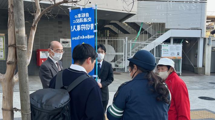 取手駅西口で副市長、警察官、母の会のかたが高校生に本制度を説明する様子
