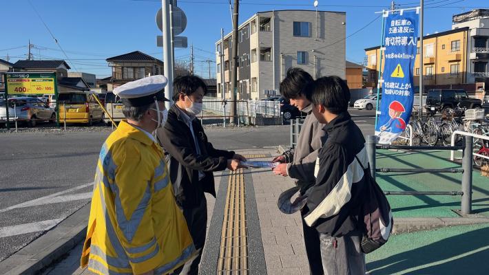 藤代駅北口自転車駐車場で警察官と市職員が高校生に本制度を説明する様子