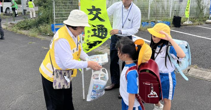取手市交通安全母の会員が小学生に交通安全を呼びかける様子