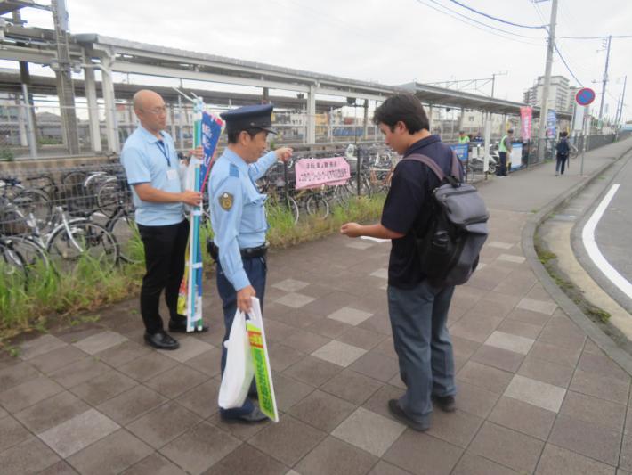 警察官及び取手市職員が高校生に自転車盗難への警戒を呼びかけている様子