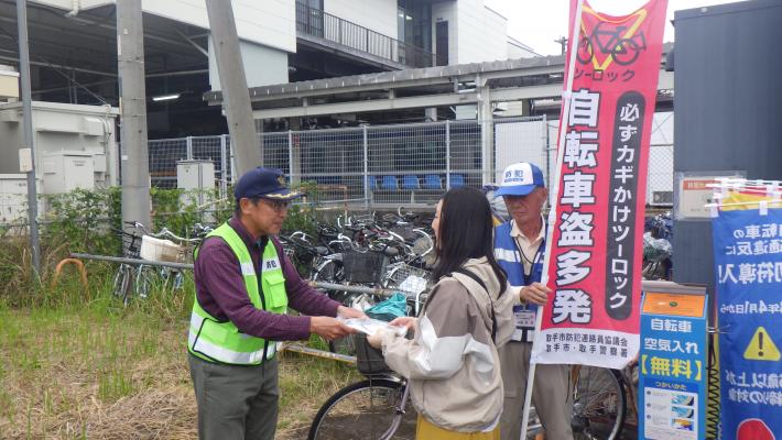 藤代駅南口自転車駐車場において、防犯連絡員及び取手市防犯活動推進員が自転車利用者に啓発品を配布している様子