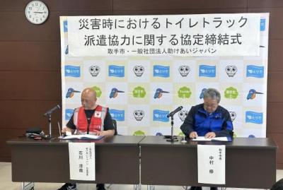 協定書に署名する助けあいジャパン代表理事と市長