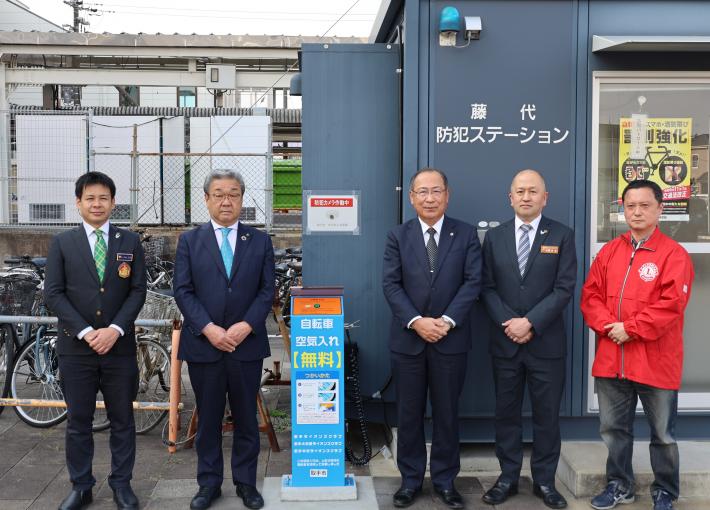 電動空気入れ設置完成式の様子。男性5人が空気入れの前に並んでいる