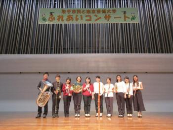 「ふれあいコンサート」看板のある舞台上で金管五重奏・木管五重奏の奏者が集合している写真。