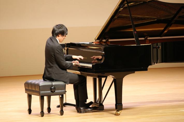 ステージの中央で演奏者がピアノを弾いている