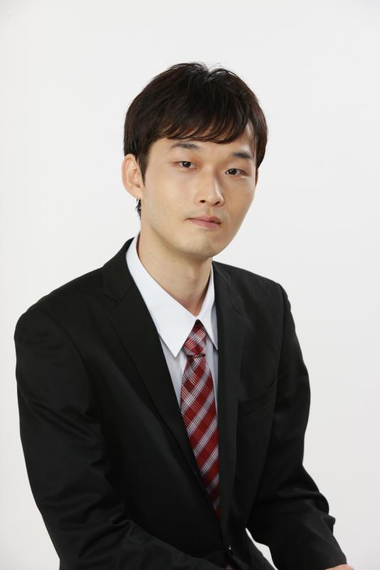 赤いチェックのネクタイをしめ、黒いスーツを着ている。有吉佑仁郎写真