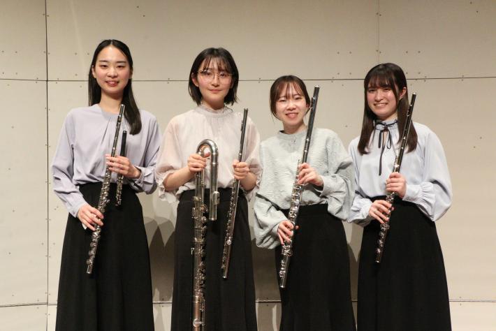 黒いスカートをはきフルートを持った4人の女性が立って並んでいる