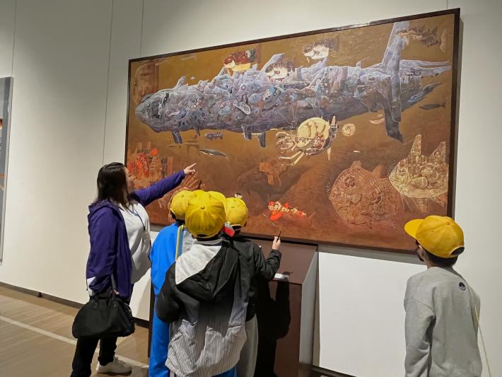 片岡啓介《空想人工魚図鑑》を前に1人の女性と4人の小学生が鑑賞している