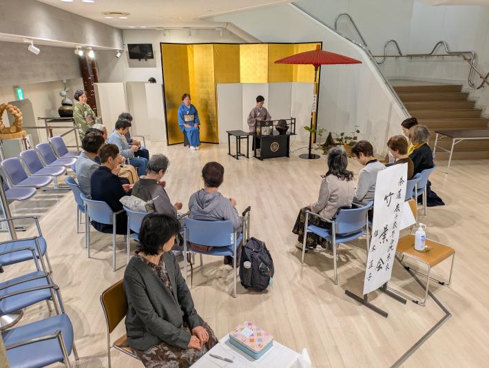 市民会館ロビーの一角に茶道の団体が設けられた茶席で、来場者が一服のおもてなしを受けています
