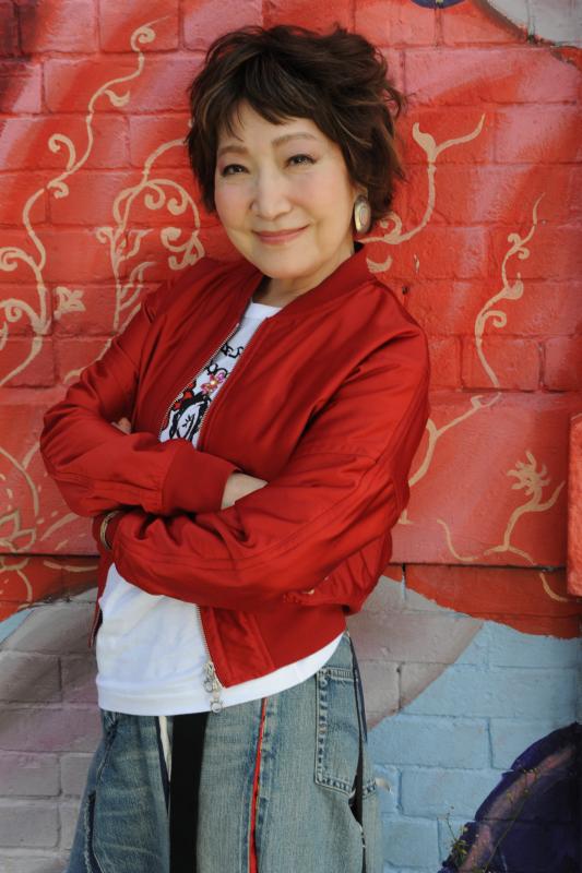 森山良子宣材写真。腕を組んだ女性が正面を向いて笑っている。