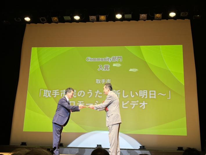 表彰式で壇上で賞状を受け取っている様子