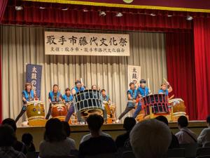 ステージで、9人の男女が和太鼓を力強くたたき演奏している様子