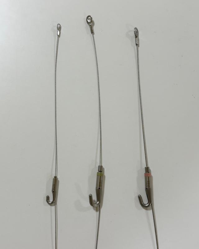 作品を壁に飾る際に使用するフックがついたワイヤー。対応でき重量が違うワイヤーが3種類並んでいる。