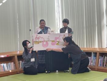 大きな絵本を広げて読み聞かせをする大人たち