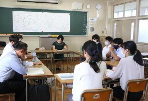 ロの字に机を並べて座り、教室内で何かを話し合う若人たち