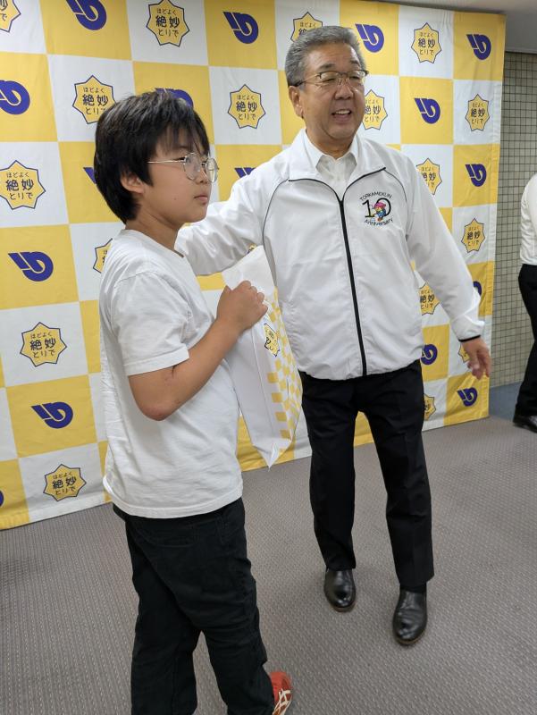 小学生の肩に大人が手を差し伸べている写真