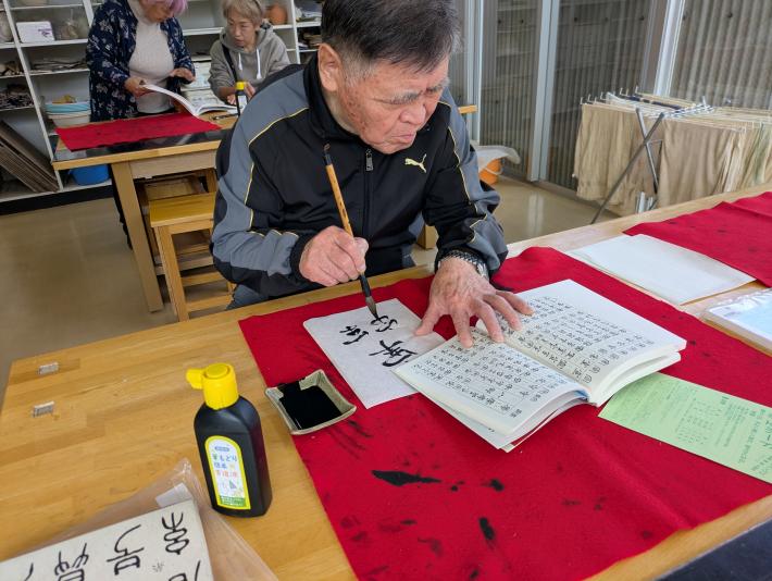 男性が毛筆で文字を試し書きしている