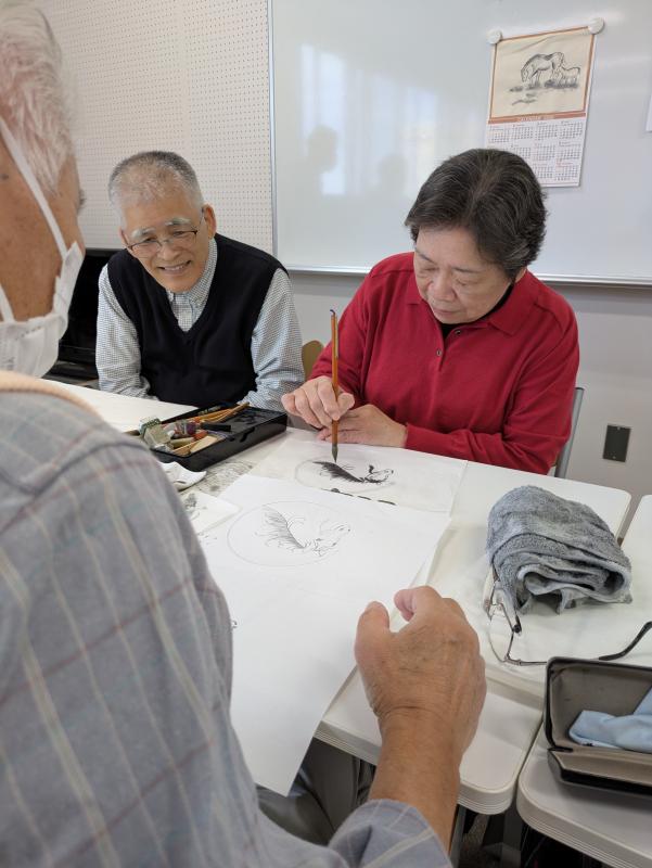 女性が水墨画の指導を受けている
