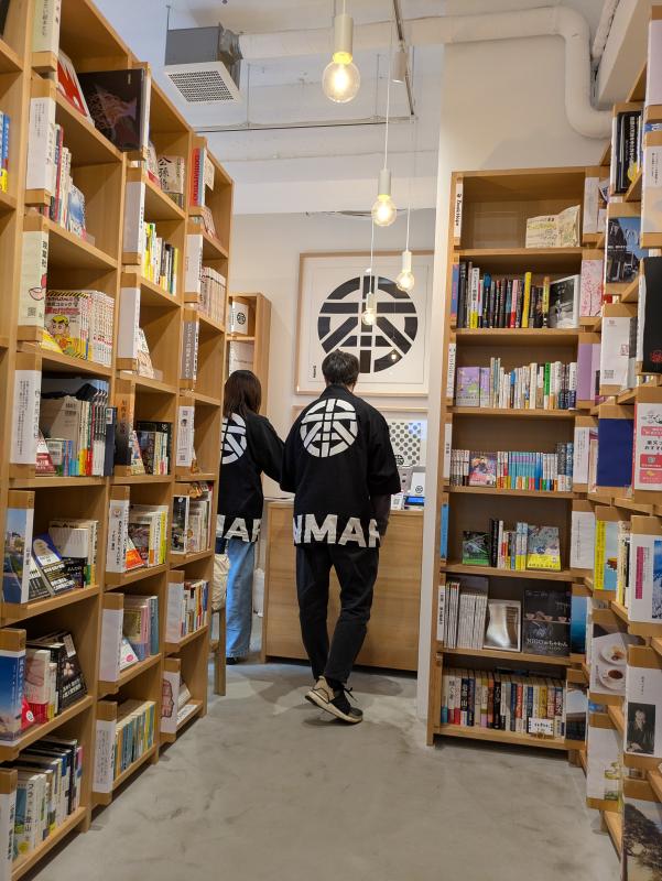 たくさんの棚日本が飾られ、丸に本のロゴが入った法被を着た人が作業している