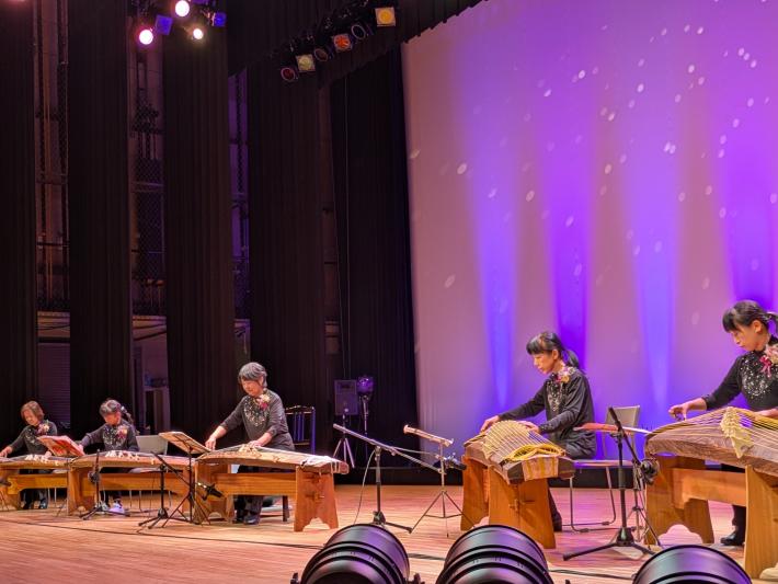 舞台上で5人の女性が箏を弾いている