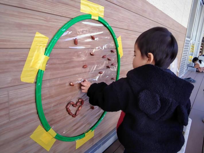 男の子が円の中にどんぐりを付けている写真