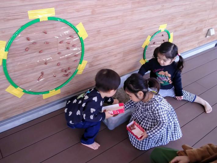 3人のお子さんが砂の箱の中からどんぐりを拾っている写真