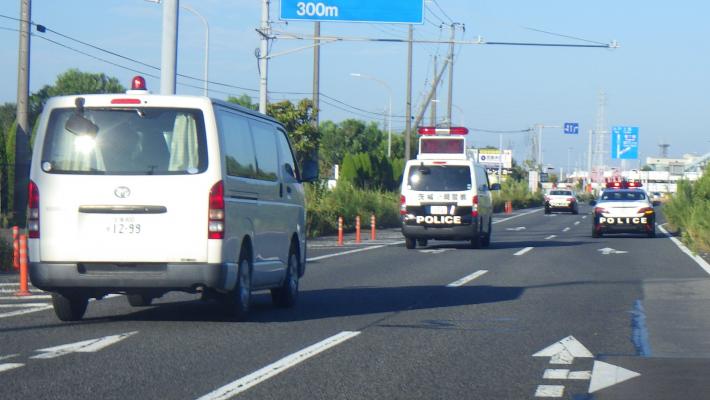 片側2車線の道路をパトカーと青パトが車列を組んで走っています。