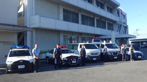 パトカーや青パトの横に、警察官や市職員が立っている写真