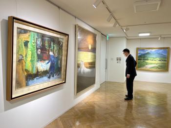 壁にかけられた大型の絵画を見る男性