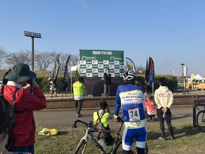 バックパネルの前に立ってあいさつをする男性