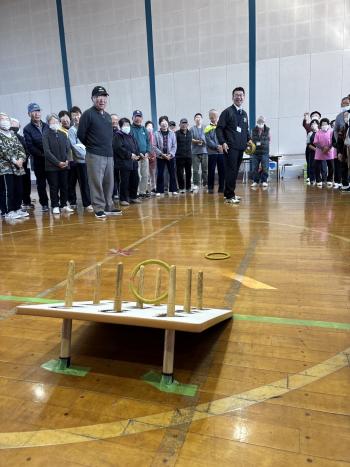 参加者に囲まれて輪投げを投げる男性