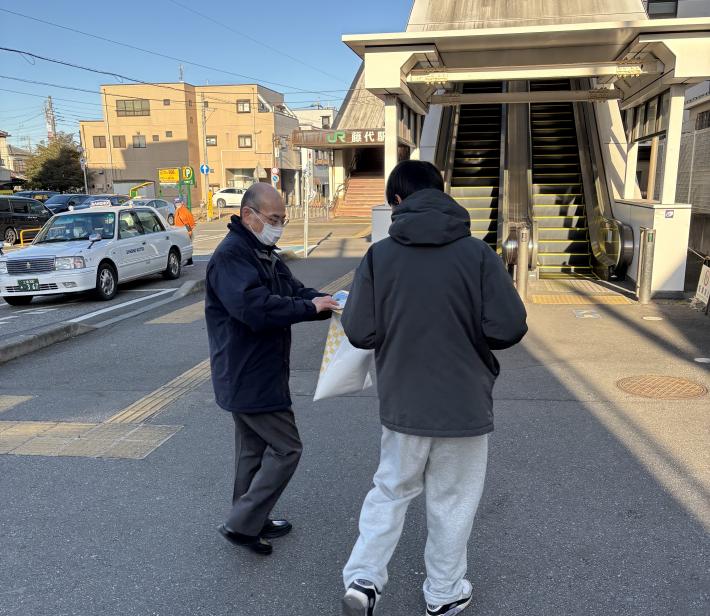 啓発グッズを配る男性と受け取る男性