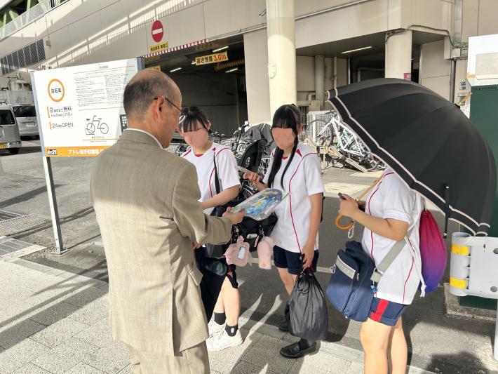 ジャージを着た学生に啓発グッズを配布する男性