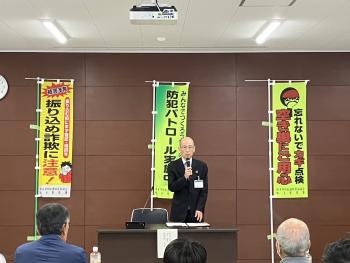 旗の前から挨拶をする男性