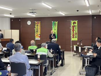 着座の参加者に向けて、旗前に立って挨拶をする男性