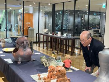 机に置かれた美術品を見る男性