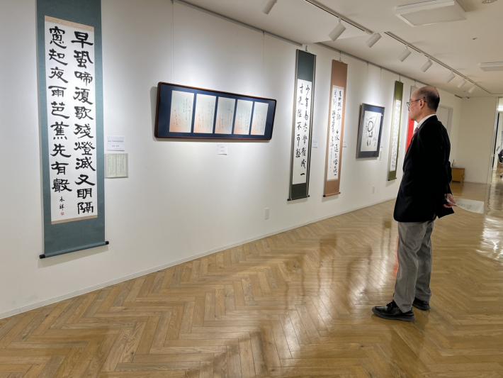 壁にかかった書を鑑賞する男性