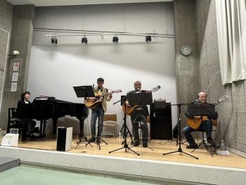 小さなステージの上でギターとピアノを伴奏する人たち