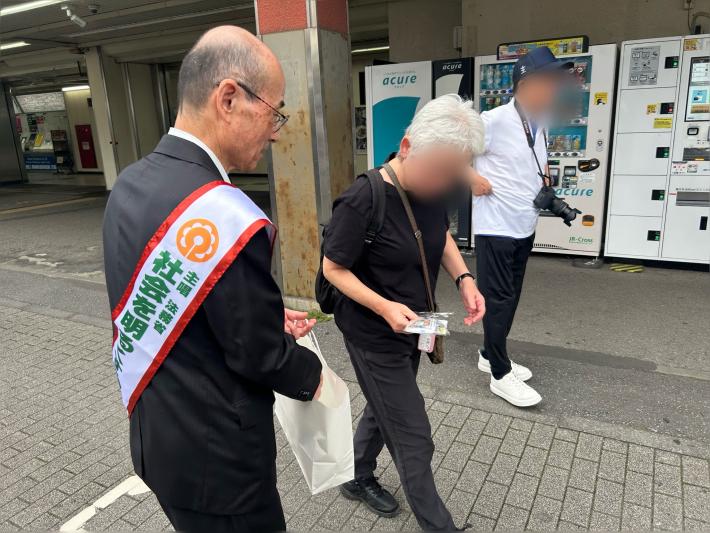 駅前の通行者に啓発グッズを配る男性