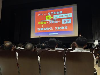 会場ステージ上にある大型スクリーンを見る参加者たち